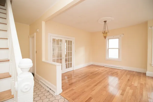 a view of empty room with wooden floor and fan