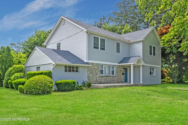 a front view of a house with a garden and trees