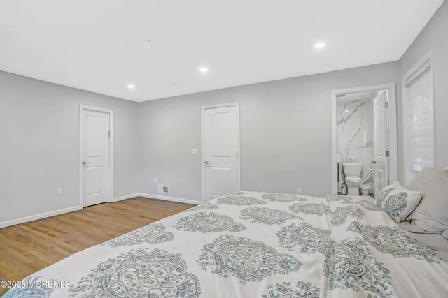 a view of a bedroom with a bed and wooden floor