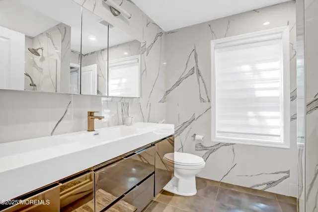 a bathroom with a sink a toilet and a large mirror