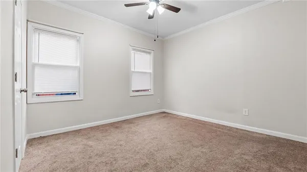 an empty room with a chandelier fan and windows