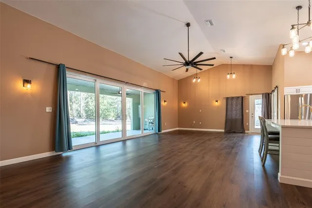 a large kitchen with cabinets a sink dishwasher a dining table and chairs with wooden floor