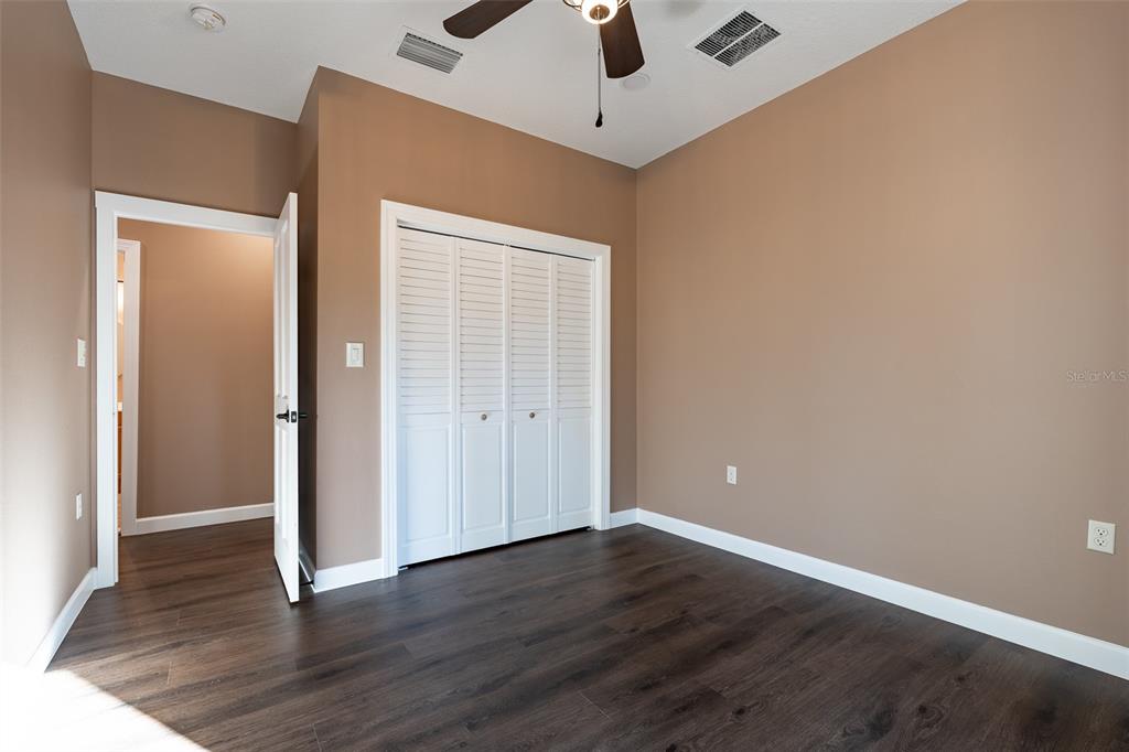 6425 Cartwrite Road Spring Hill, FL 34609 - Photo 44 of 74 an empty room with wooden floor cabinet and a ceiling fan