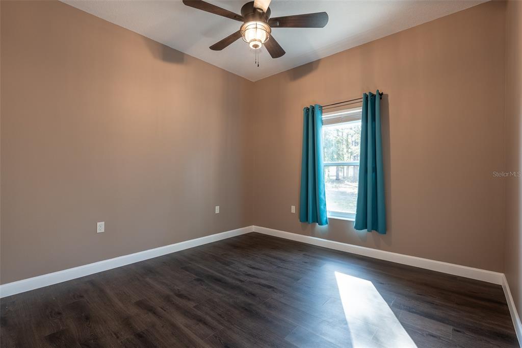 6425 Cartwrite Road Spring Hill, FL 34609 - Photo 47 of 74 an empty room with wooden floor chandelier fan and windows