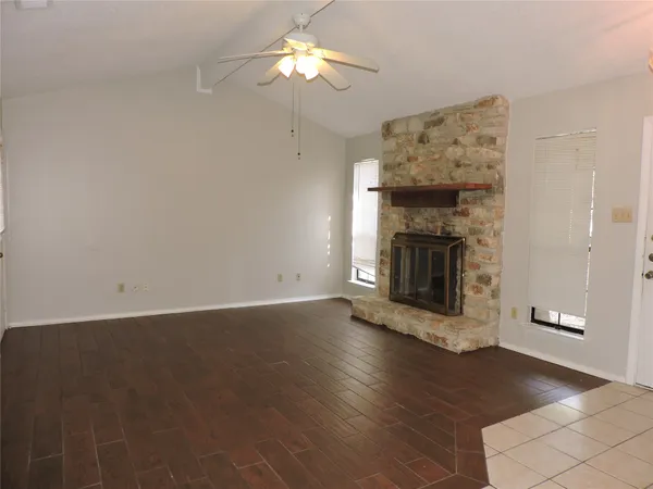 an empty room with wooden floor a fireplace and windows
