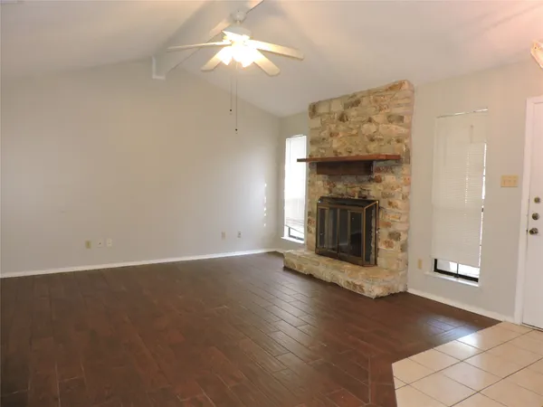 an empty room with wooden floor fireplace cabinet and windows