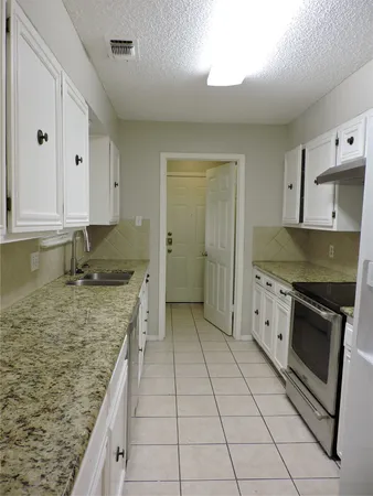 a kitchen with granite countertop a sink stove and cabinets