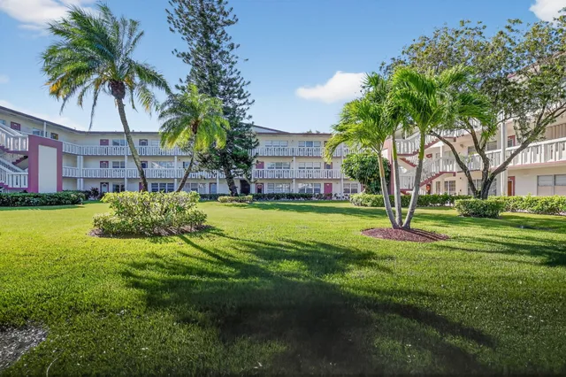 a view of a house with a big yard and palm trees