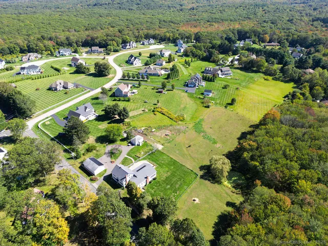 an aerial view of residential houses with outdoor space and trees all around