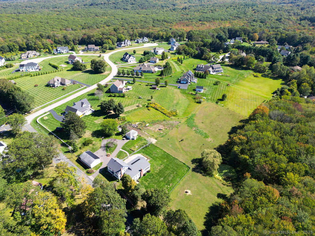 an aerial view of residential houses with outdoor space and trees all around