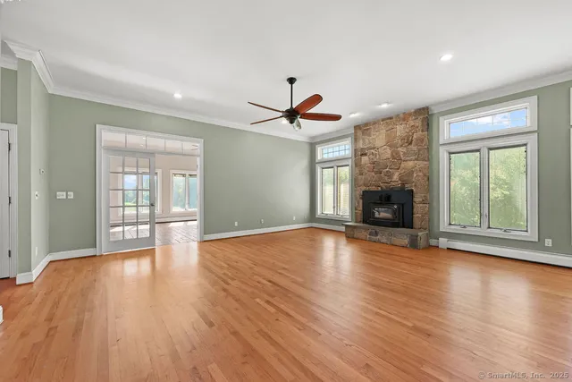 an empty room with wooden floor a fireplace and windows