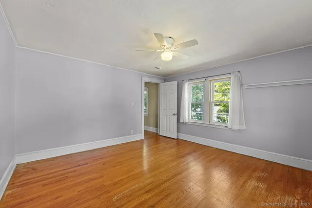 a view of an empty room with a window and wooden floor