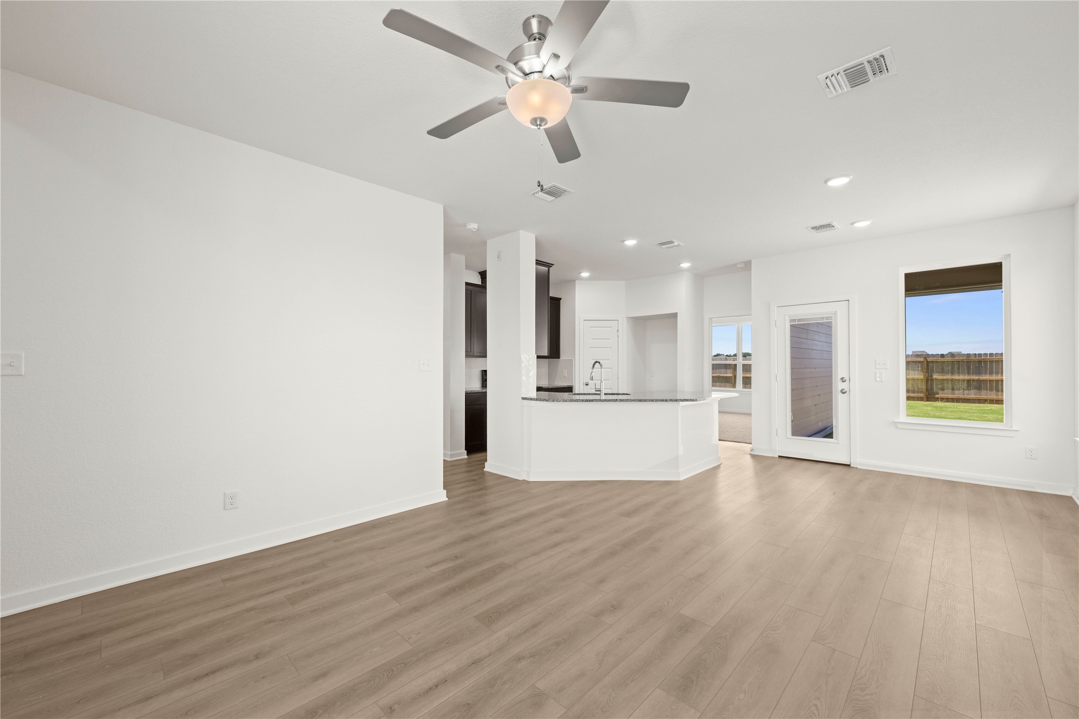 228 Gus Loop Georgetown, TX 78626 - Photo 13 of 19 An open concept living area showcases durable plank flooring, flowing into a well-appointed kitchen with a breakfast bar.