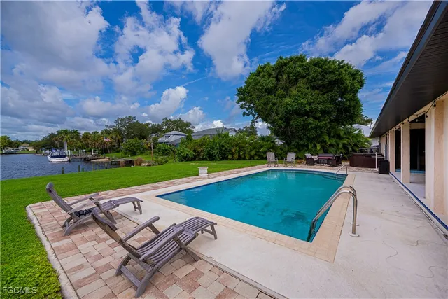 a view of a swimming pool and lounge chairs in back yard of the house
