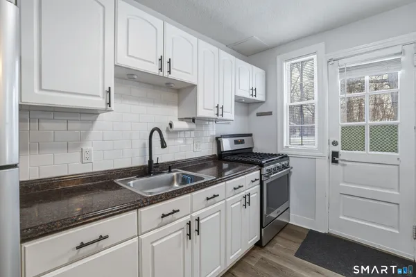 a kitchen with granite countertop white cabinets and white appliances