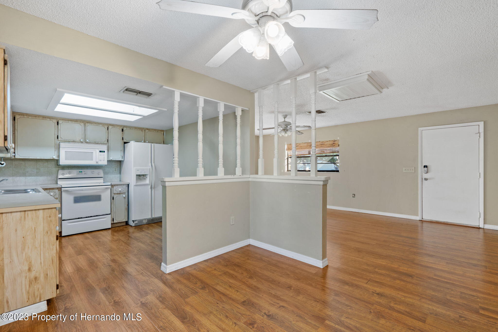 10479 Thornberry Drive Spring Hill, FL 34608 - Photo 14 of 44 a kitchen with wooden floors and white cabinets