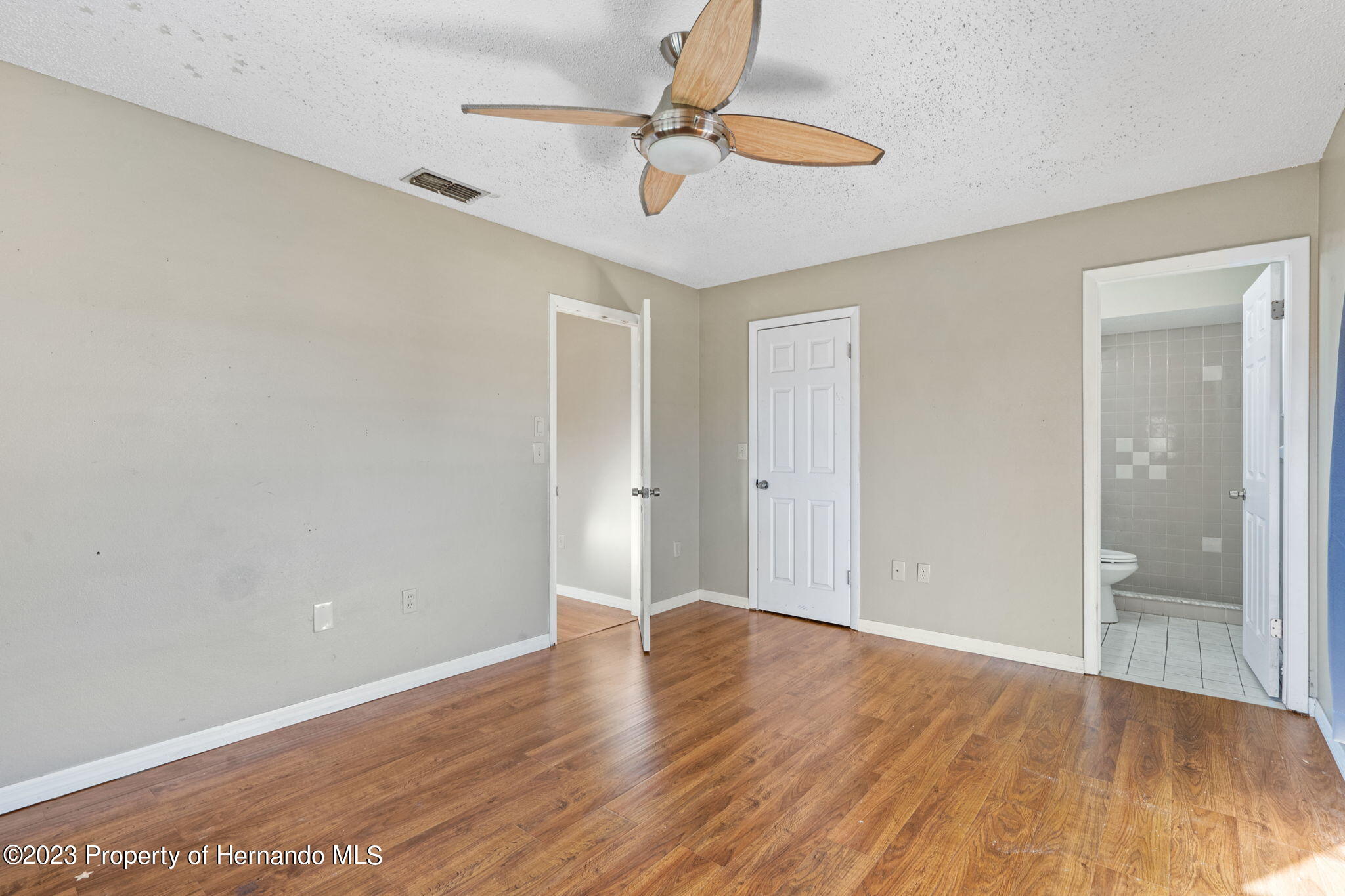 10479 Thornberry Drive Spring Hill, FL 34608 - Photo 21 of 44 an empty room with wooden floor fan and windows