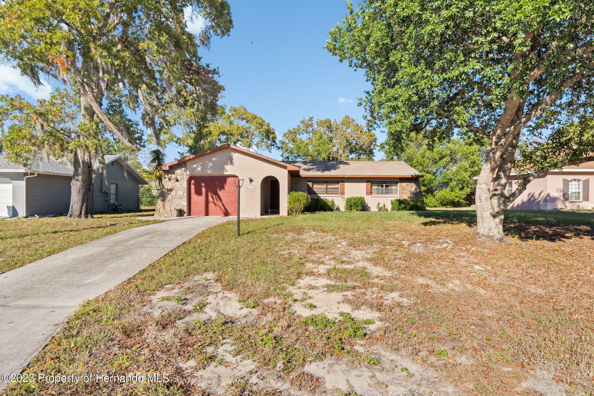 10479 Thornberry Drive Spring Hill, FL 34608 - Photo 5 of 44 a view of a white house with a large tree with flower plants