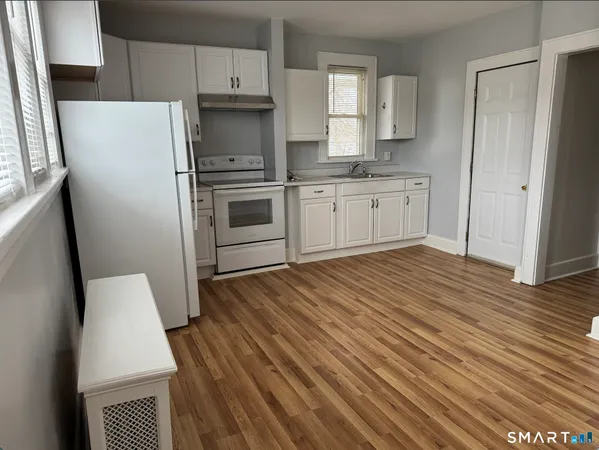 a kitchen with wooden floors white cabinets and stainless steel appliances