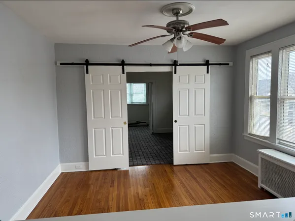 a view of empty room with wooden floor and fan