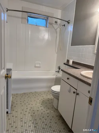 a bathroom with a granite countertop bathtub shower sink vanity and toilet
