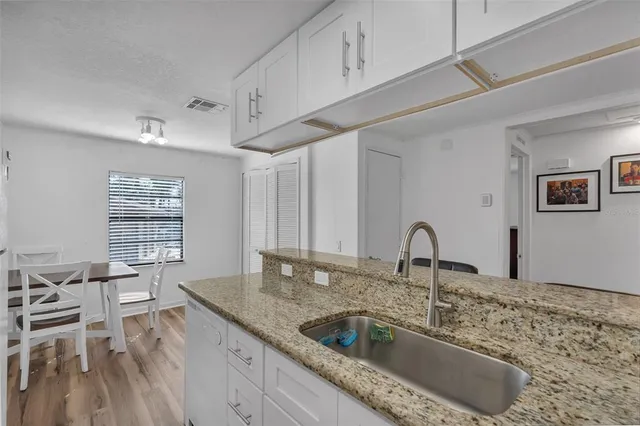 a kitchen with granite countertop a sink a counter top space and cabinets