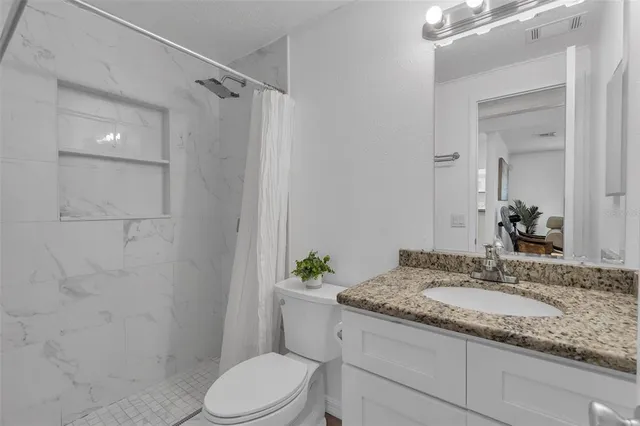 a bathroom with a granite countertop sink toilet and shower