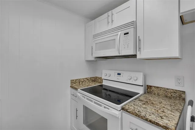 a kitchen with granite countertop white cabinets and a stove top oven
