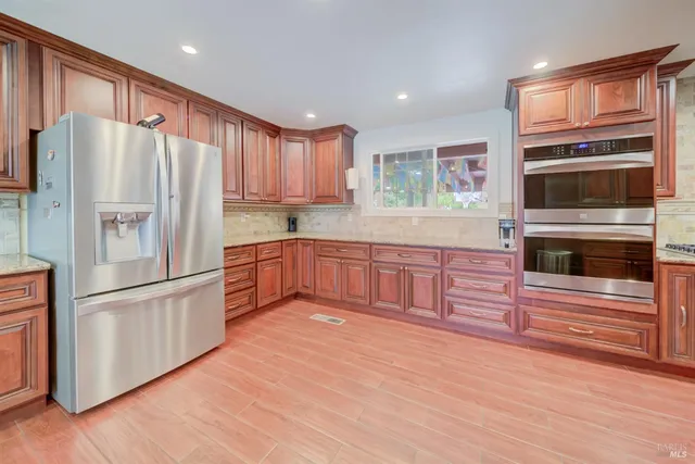 a large kitchen with stainless steel appliances granite countertop a stove a sink and a microwave