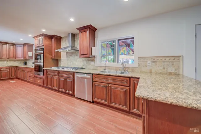 a kitchen with stainless steel appliances granite countertop wooden cabinets a refrigerator and a sink