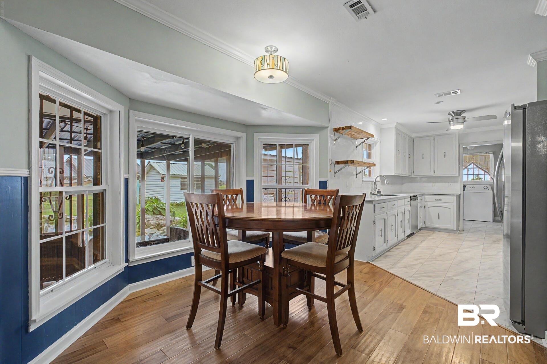 3791 Robinsonville Road Atmore, AL 36502 - Photo 29 of 47 Kitchen and dining area featuring wood-finish flooring, white cabinetry, a stainless steel refrigerator, a ceiling fan, and built-in open shelving