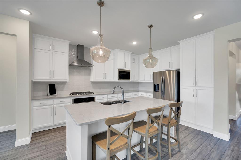 1601 Bear Path Way Gunter, TX 75058 - Photo 12 of 40 a kitchen with stainless steel appliances a kitchen island a stove a table and chairs in it