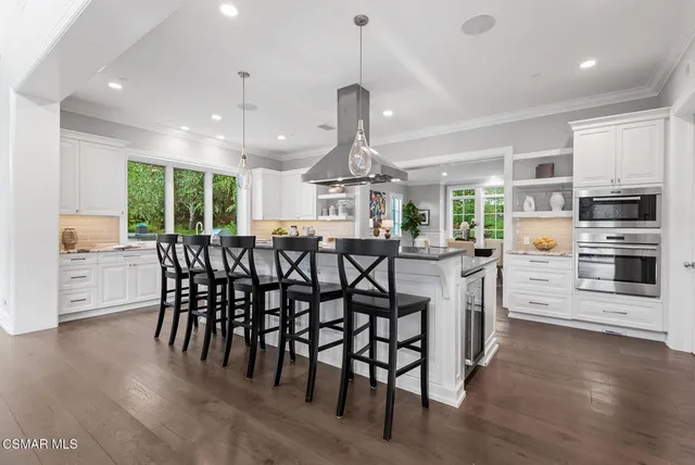 a kitchen with stainless steel appliances kitchen island granite countertop a dining table chairs and granite counter tops