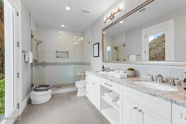 a bathroom with a double vanity sink toilet and a mirror