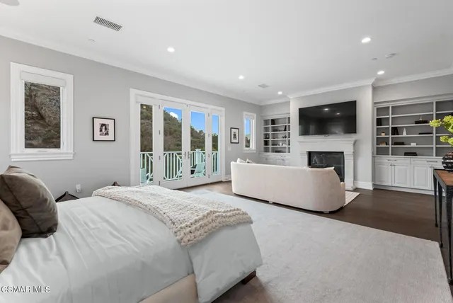 a spacious bedroom with a large bed a flat tv screen and a fireplace