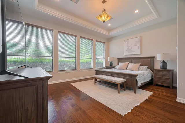 a spacious bedroom with a bed a chandelier and a large window