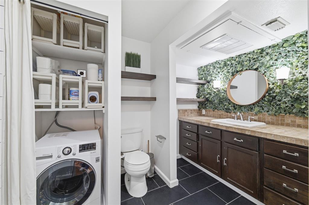 4837 Cedar Springs Road, Unit 311 Dallas, TX 75219 - Photo 17 of 17 Bathroom with washer / dryer, decorative backsplash, vanity, dark tile patterned floors, and a closet