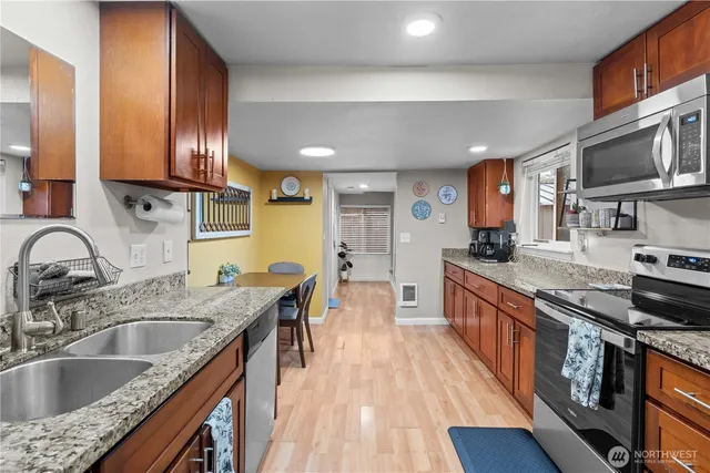 a kitchen with stainless steel appliances granite countertop a sink stove and wooden cabinets