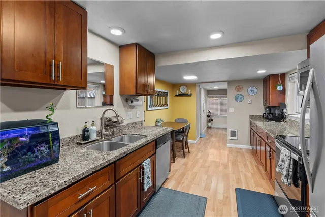 a large kitchen with stainless steel appliances granite countertop a stove a sink dishwasher and cabinets with wooden floor