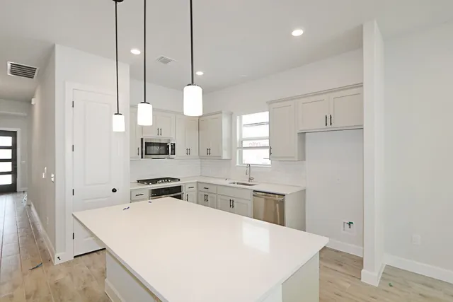 a large white kitchen with a sink a stove and refrigerator