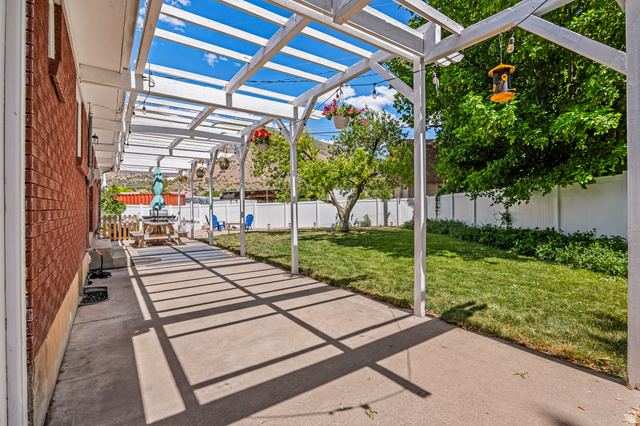 480 North 150 E Street Springville, UT 84663 - Photo 34 of 36 Concrete patio featuring a white pergola structure, brick exterior, and a manicured lawn