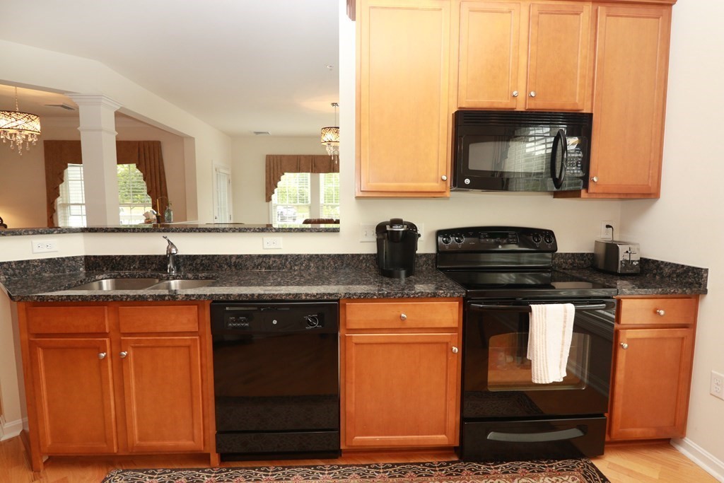 7 Morgan Drive, Unit 104 Natick, MA 01760 - Photo 3 of 26 a kitchen with stainless steel appliances granite countertop a sink stove and microwave