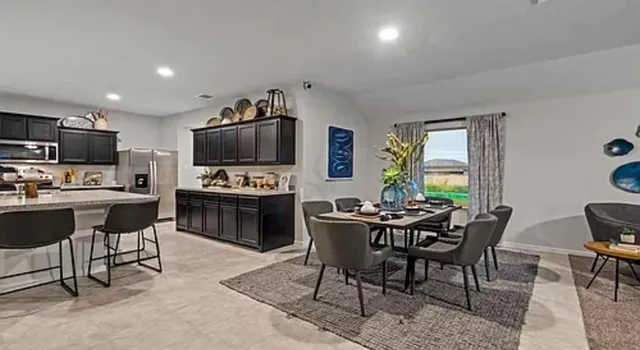 a kitchen with stainless steel appliances granite countertop a stove a sink a microwave a refrigerator and chairs