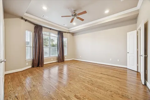 an empty room with wooden floor and ceiling fan