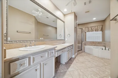 a spacious bathroom with a granite countertop double vanity sink a mirror and a bathtub