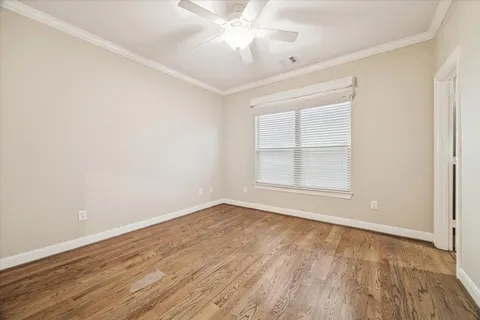 an empty room with wooden floor chandelier fan and windows