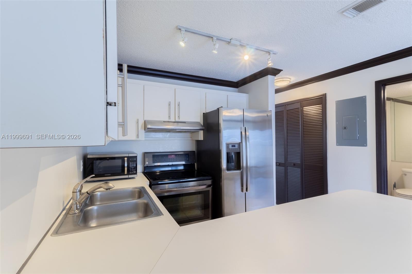13874 Southwest 64th Street Miami, FL 33183 - Photo 11 of 25 a kitchen with a refrigerator a sink and cabinets