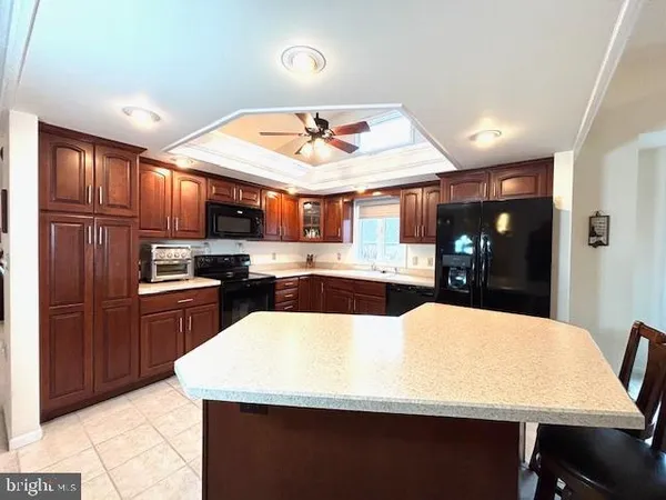 a large kitchen with stainless steel appliances kitchen island granite countertop a refrigerator a sink dishwasher a dining table and chairs with wooden floor