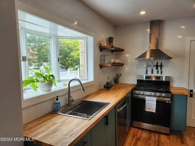 a kitchen with stainless steel appliances granite countertop a sink a stove and a wooden floors