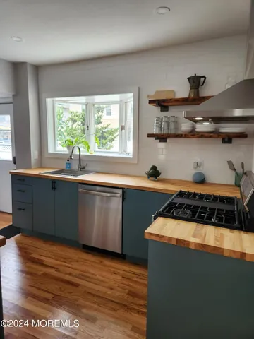 a kitchen with stainless steel appliances granite countertop a sink a stove a window and cabinets